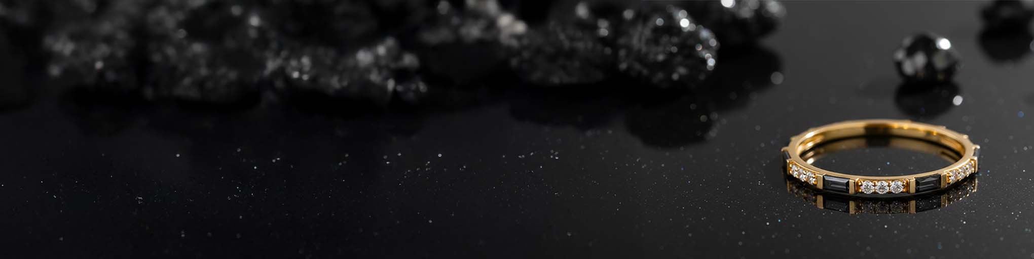 18K yellow gold black diamond wedding ring with white diamond pavé on glittering black background