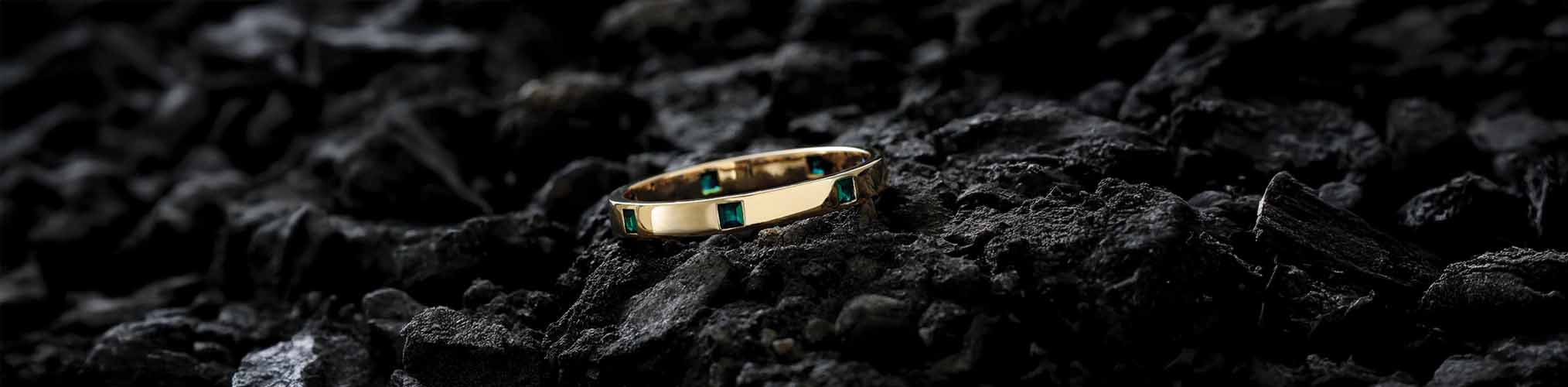 18K yellow gold men's ring set with emeralds, masculine wedding ring on black volcanic stone