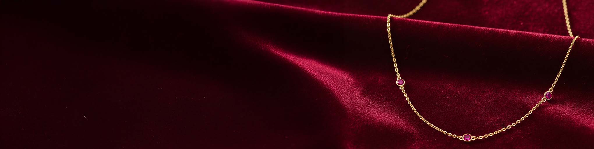 Vermeil necklaces set with pink rubies on burgundy velvet background, fine jewellery precious stones gold vermeil
