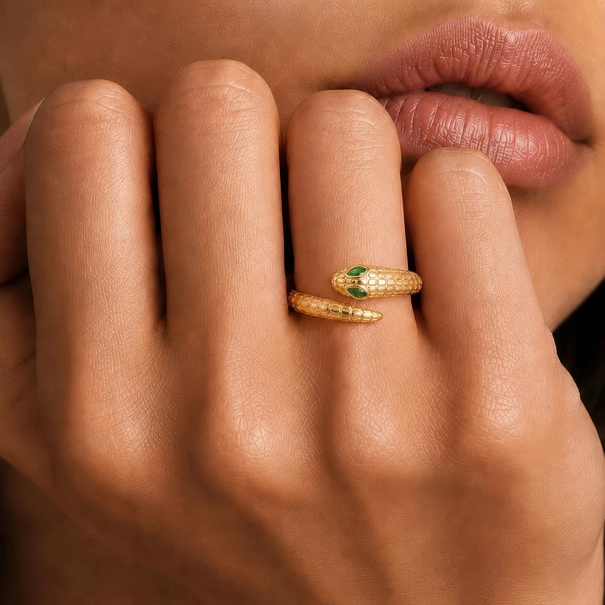 Méhen yellow gold snake ring worn on the finger, marquise emerald eyes