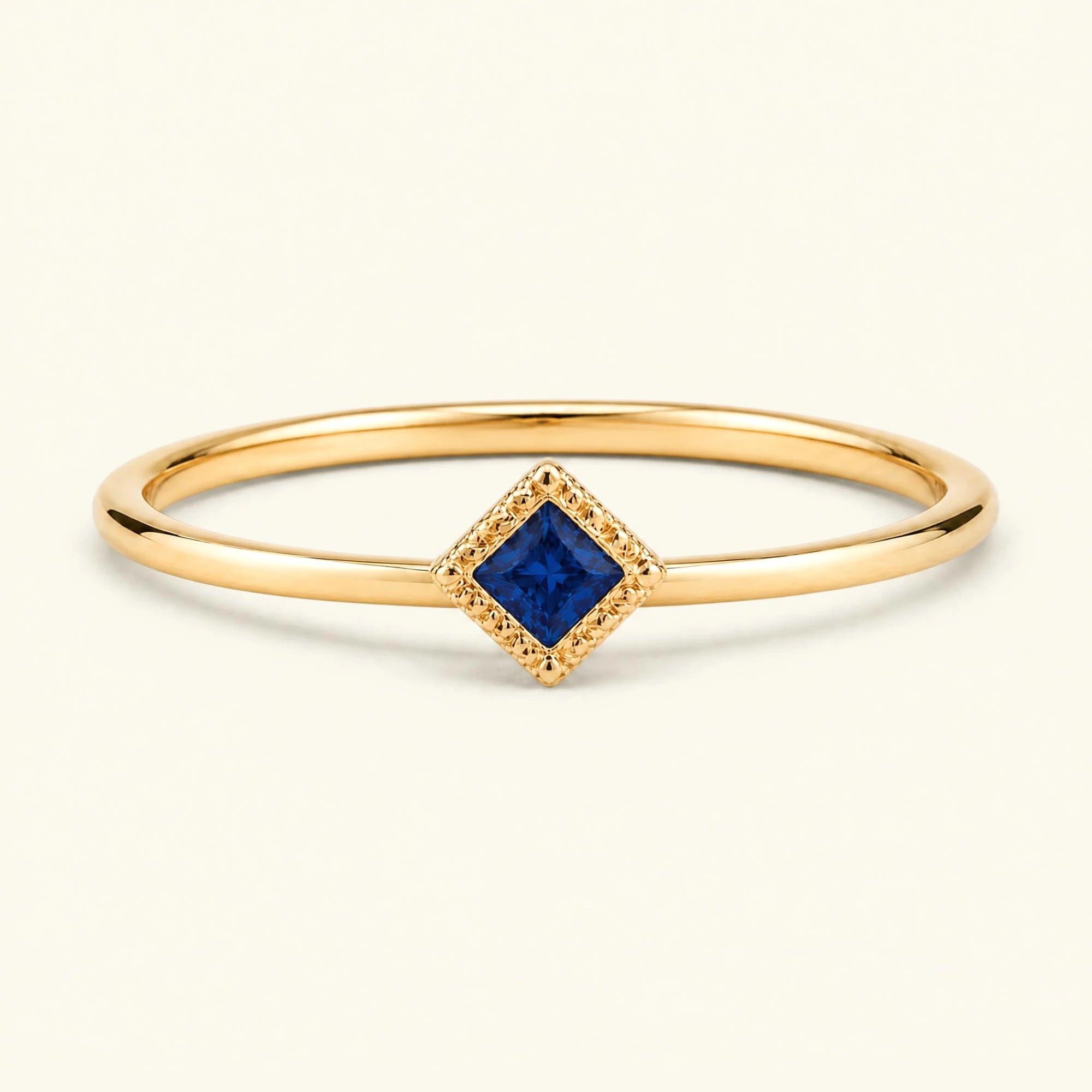 Bague de fiançailles vintage Indrani — solitaire saphir taille princesse 4 mm, pierre carrée sertie grènetis (milgrain), en or jaune 18 carats