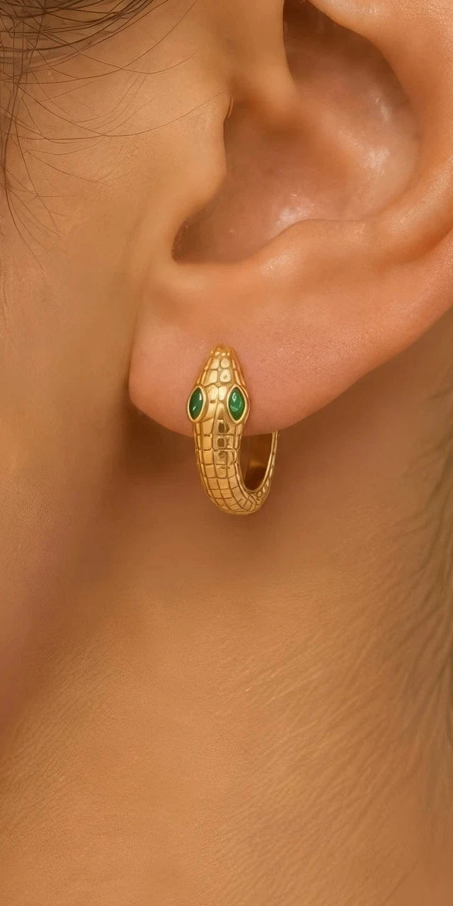 Créole serpent Méhen en or jaune portée à l'oreille, tête relevée aux yeux d'émeraude marquise