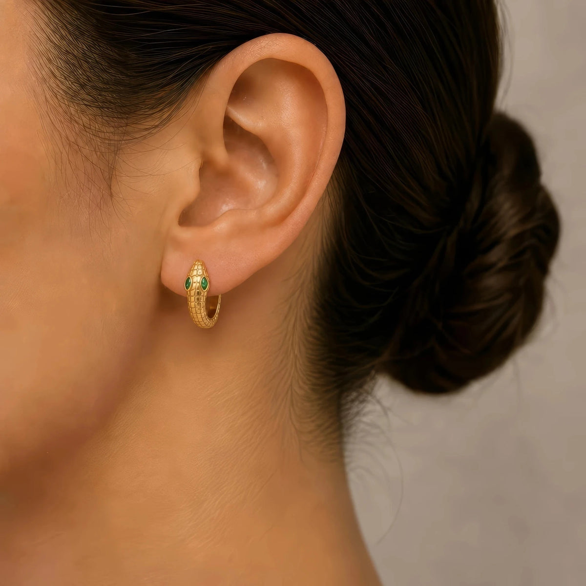 Méhen yellow gold snake hoop worn on the ear, raised head with marquise emerald eyes