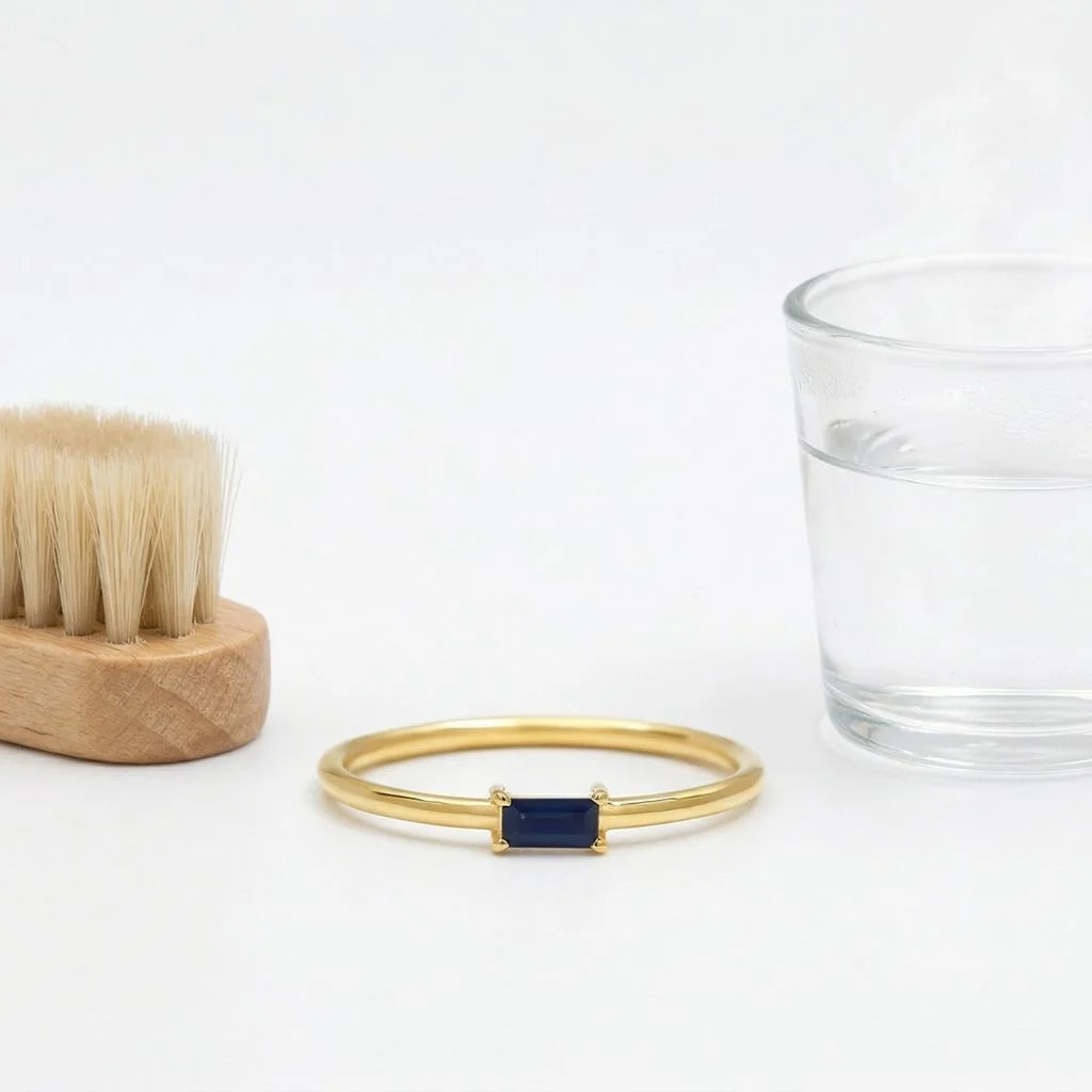 18ct Yellow Gold ring set with a baguette Sapphire, with a soft brush and a glass of lukewarm water