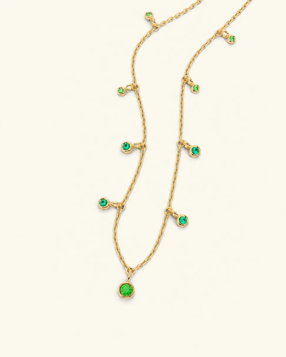 Collier Megha en or jaune orné de pendants d'émeraudes et tsavorites, dégradé Émeraude Canopée sur fond crème