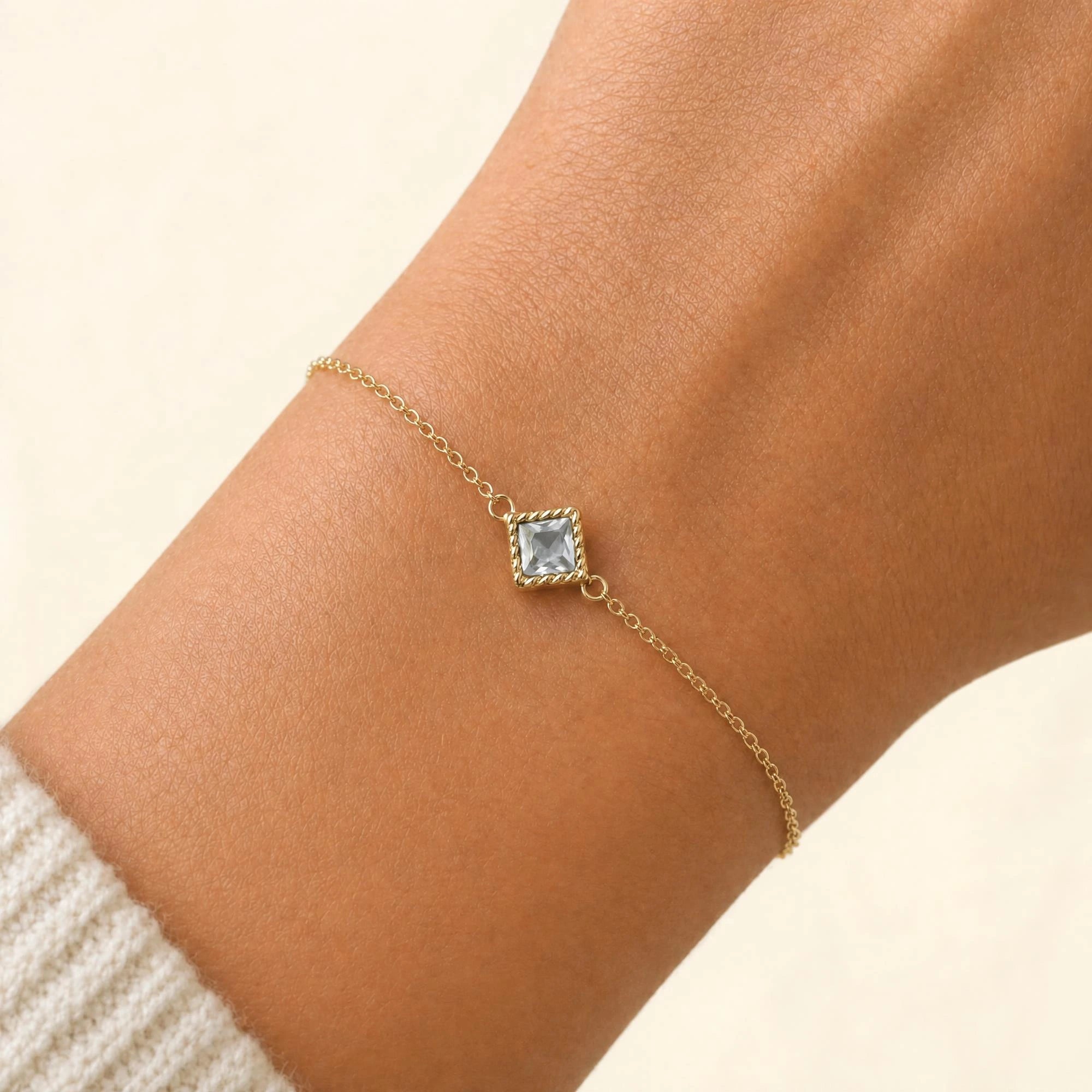 Indrani diamond bracelet worn on the wrist, princess-cut solitaire in twisted rope setting, 18K yellow gold